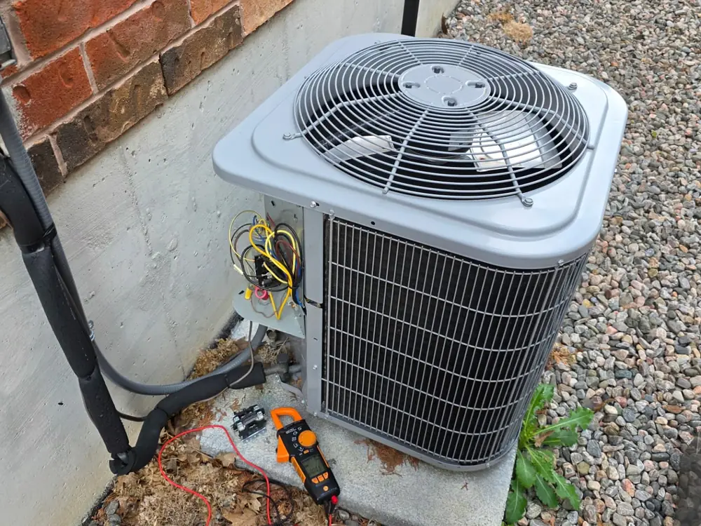 Outdoor HVAC system being serviced beside a brick home